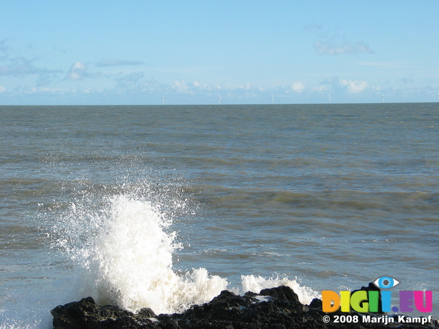 24240 Waves crashing on beach wind mills